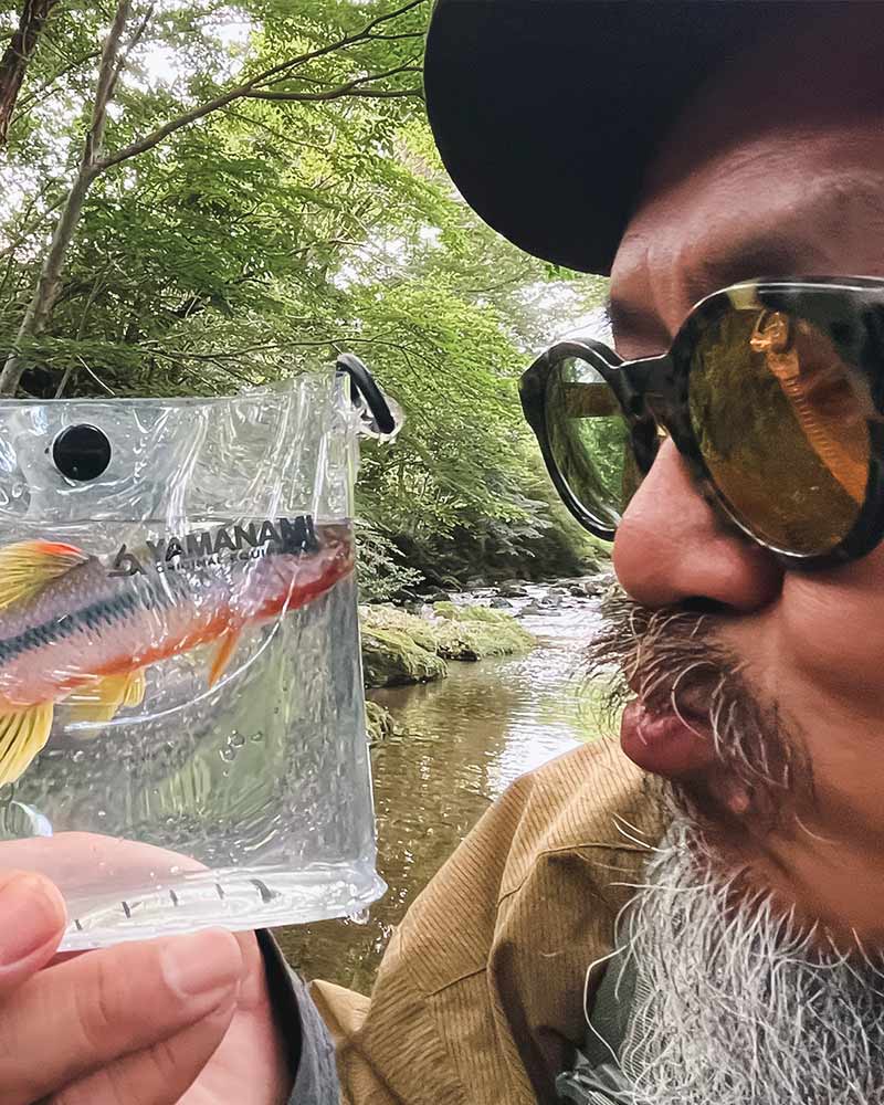 透明ケースのカワムツを眺めるアングラー