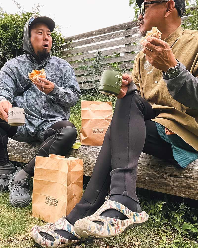 釣りの合間にベンチでパンを食べるアングラー